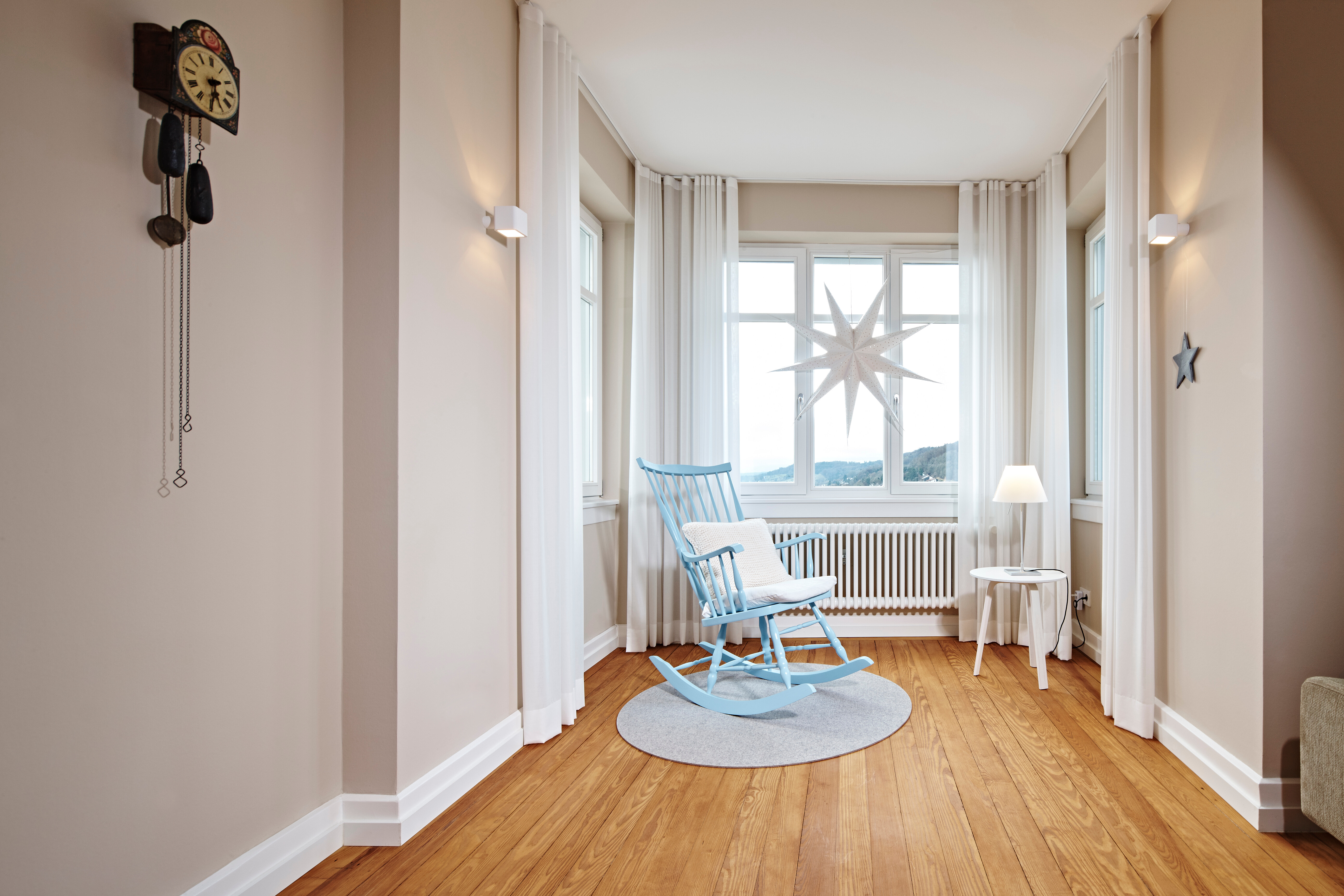 Der Schaukelstuhl (Erbstück) lädt ein zum Verweilen in der stimmungsvollen Umgebung mit warmen und weichen Textilien.