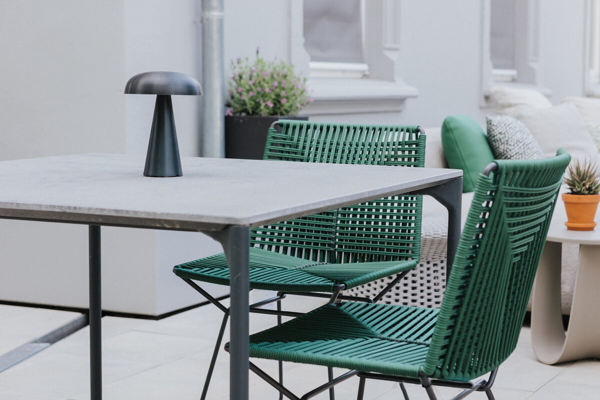 Zwei grüne Flechtstühle an einem Tisch mit mobiler Leuchte auf der Terrasse bei Seipp Wohnen in Waldshut