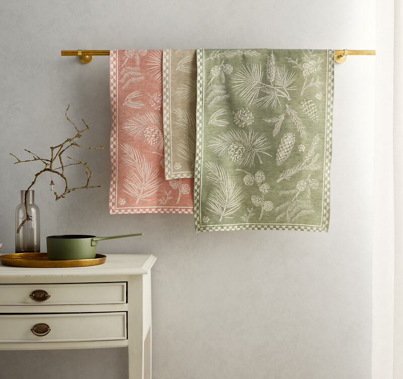 Drei gemusterte Geschirrtücher in Rosé und Salbeigrün an goldener Stange