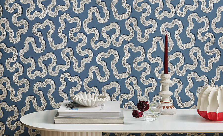 Blaue Tapete mit geschwungenem, organischem Muster hinter weißem Tisch