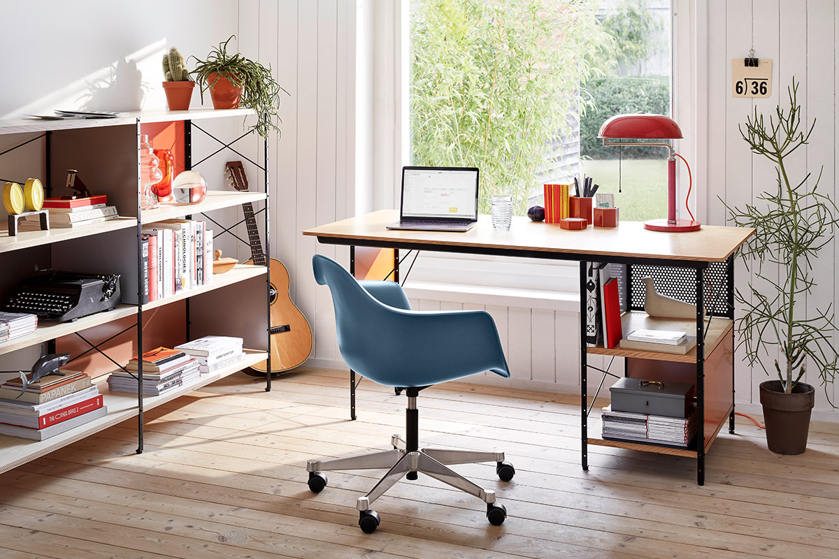 Ein stilvolles Homeoffice mit ikonischen Vitra Möbeln. Die Eames Storage Unit und Eames Desk Unit bieten Stauraum und Arbeitsfläche, ergänzt durch den PACC Plastic Chair. Der Raum wirkt hell und freundlich, ideal für kreatives Arbeiten.