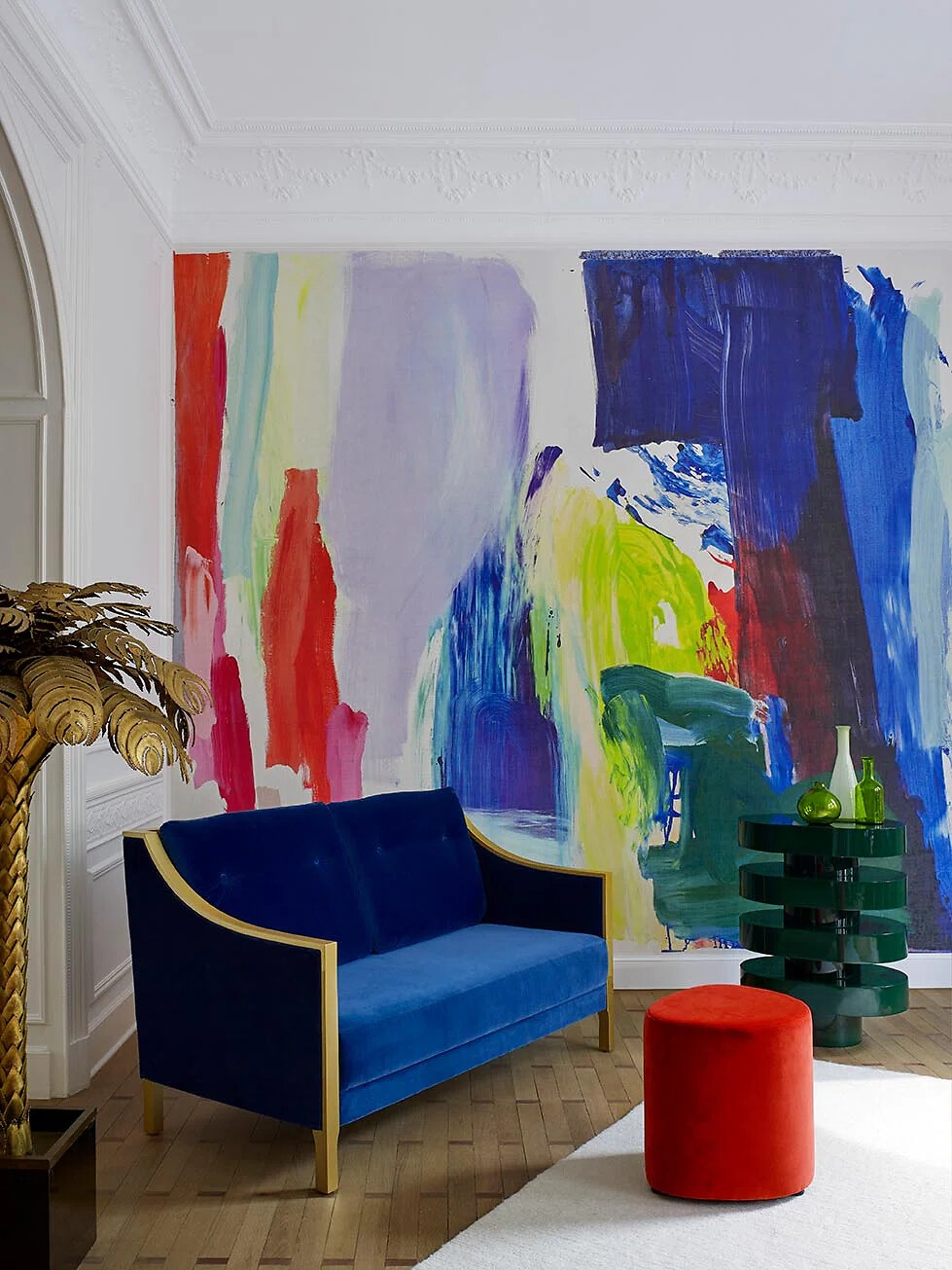 Farbintensive Wandgestaltung mit abstrakten Pinselstrichen hinter blauem Sofa