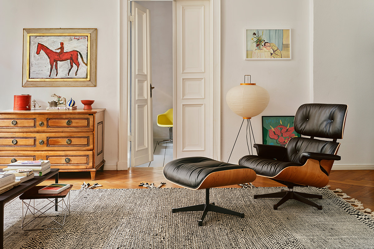 Das Wohnzimmer besticht mit ikonischen Vitra Möbeln. Der bequeme Eames Lounge Chair mit Ottoman lädt zum Entspannen ein. Ergänzt wird die Szene durch den minimalistischen LTR Table und eine stimmungsvolle Akari Stehleuchte.