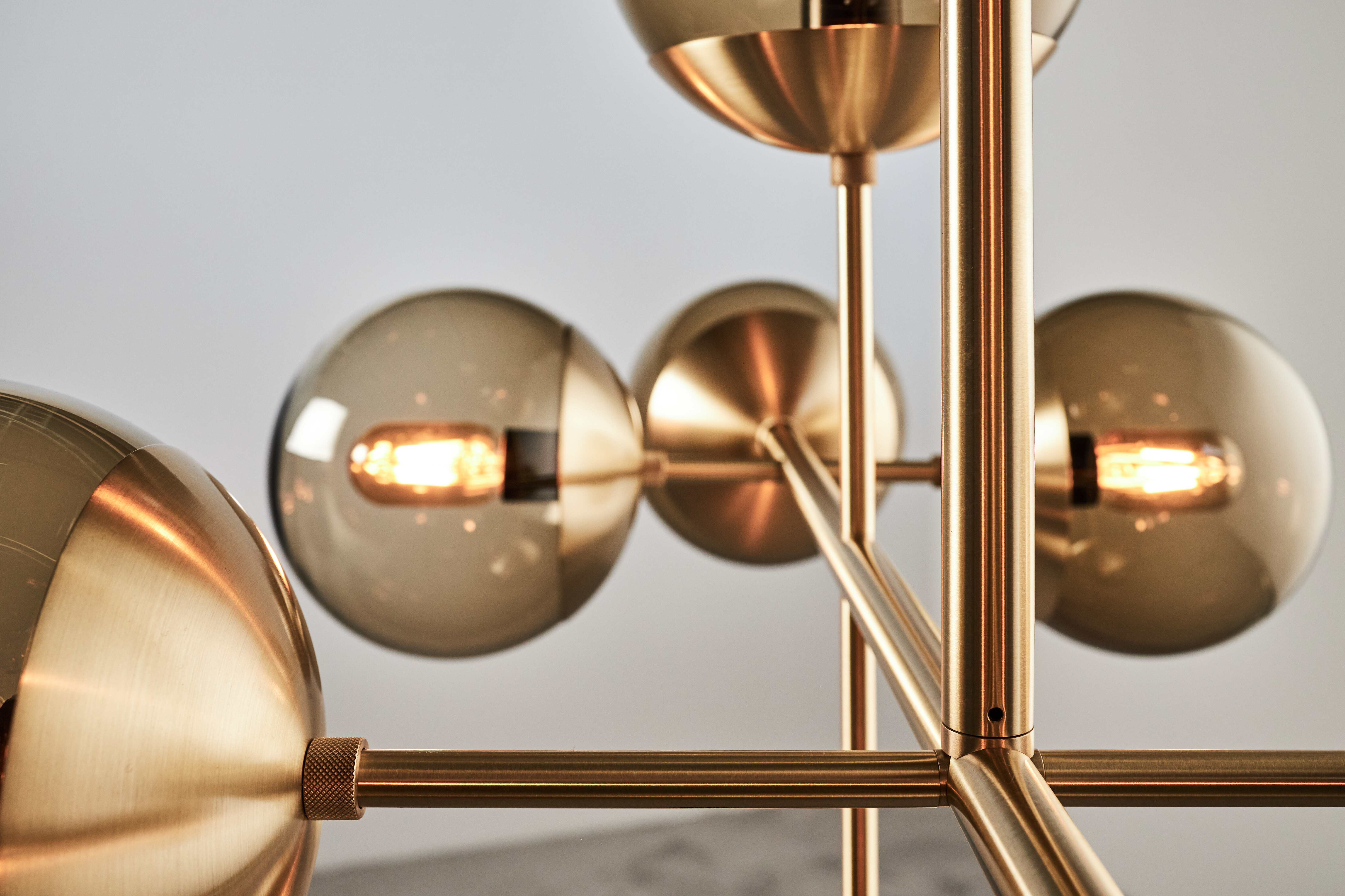 Detailaufnahme einer goldfarbenen Leuchte mit getönten Glaskugeln und Leuchtmittel