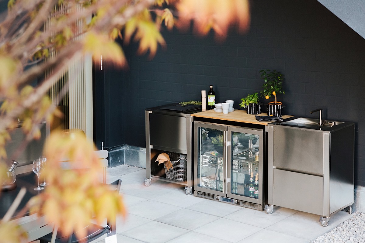 Edelstahl-Outdoorküche von Jokodomus auf Terrasse mit Spüle, Weinkühlschrank und Schneidebrett. Kompakte Lösung für stilvolles Outdoorcooking.