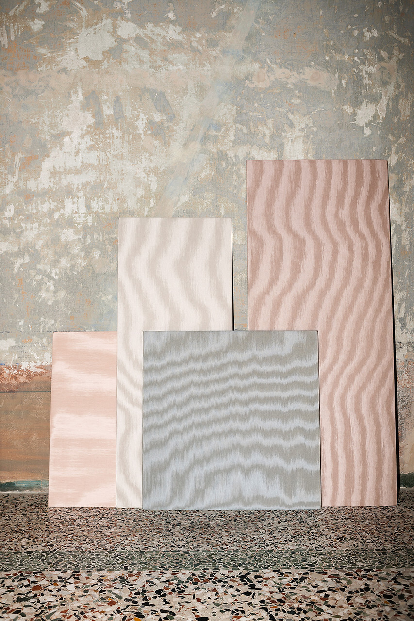 Vier aufgestellte Stoffpaneele in zarten Wellenmustern vor strukturierter Wand und Steinboden