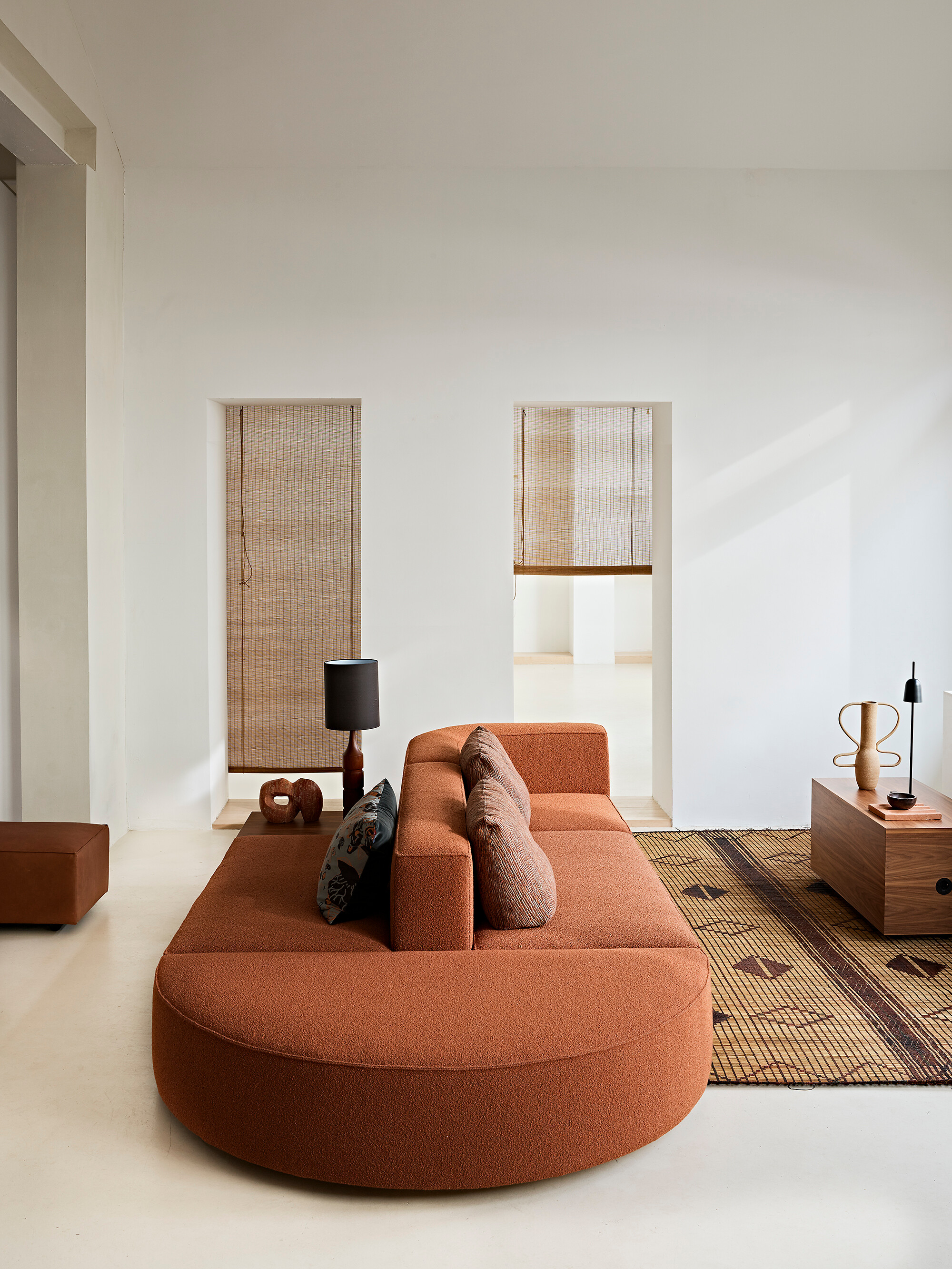 Orangefarbenes Sofa in modernem Interieur, zwei Durchgänge mit Rollos