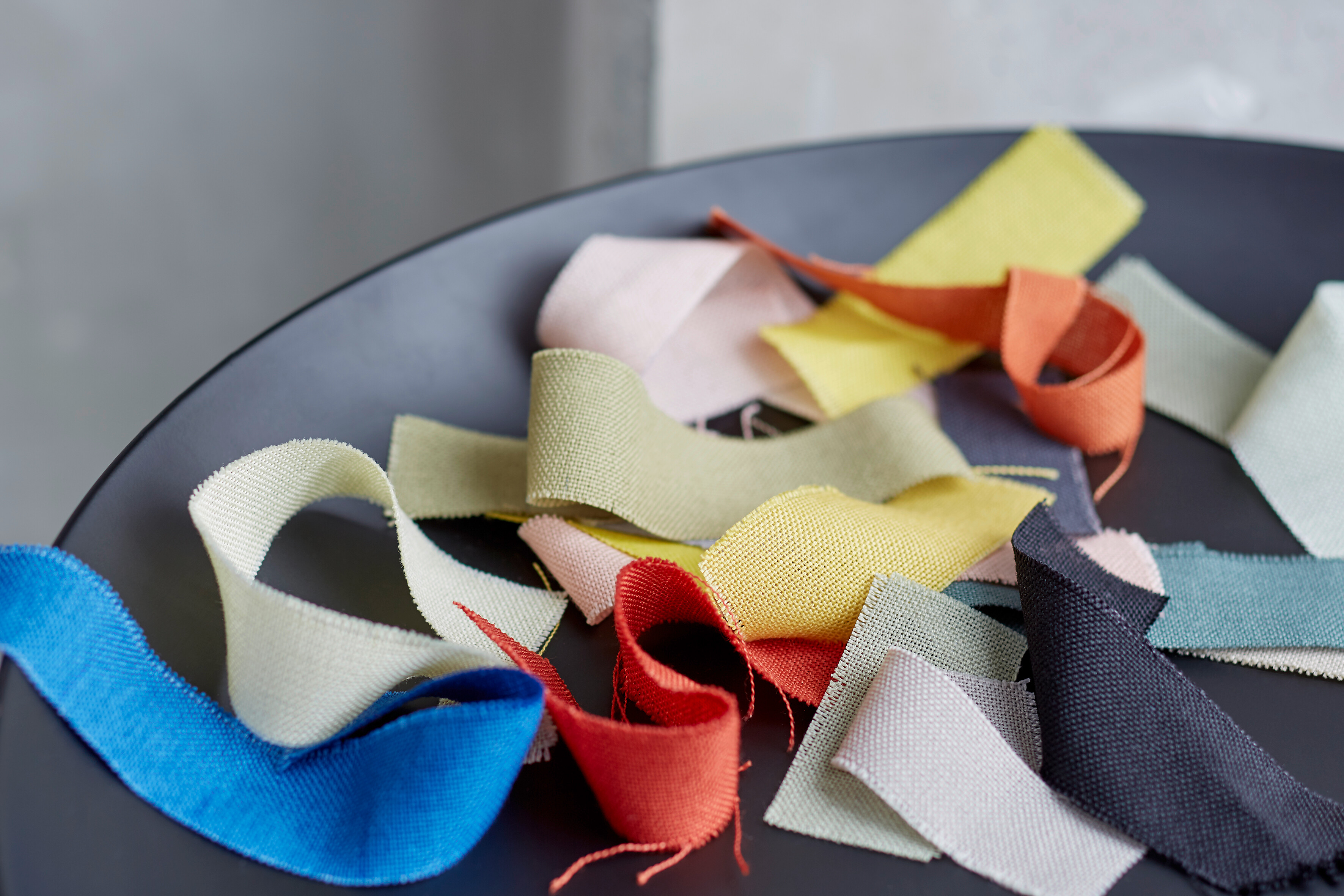 Stoffmuster in verschiedenen Farben auf dunkler runder Fläche, aufgenommen in Nahaufnahme