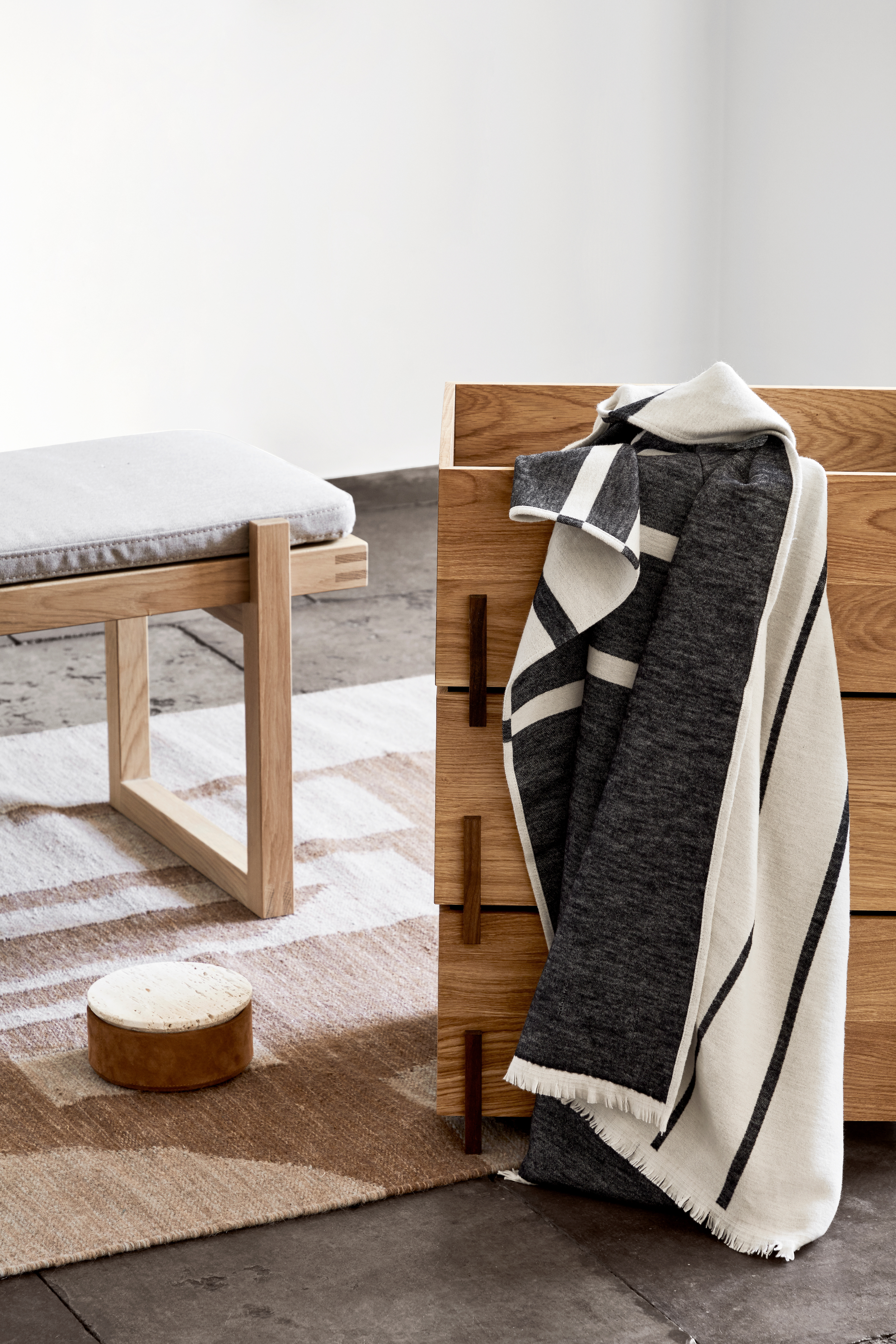 Bank mit heller Polsterung, Holzmöbel und Textilien auf gewebtem Teppichboden