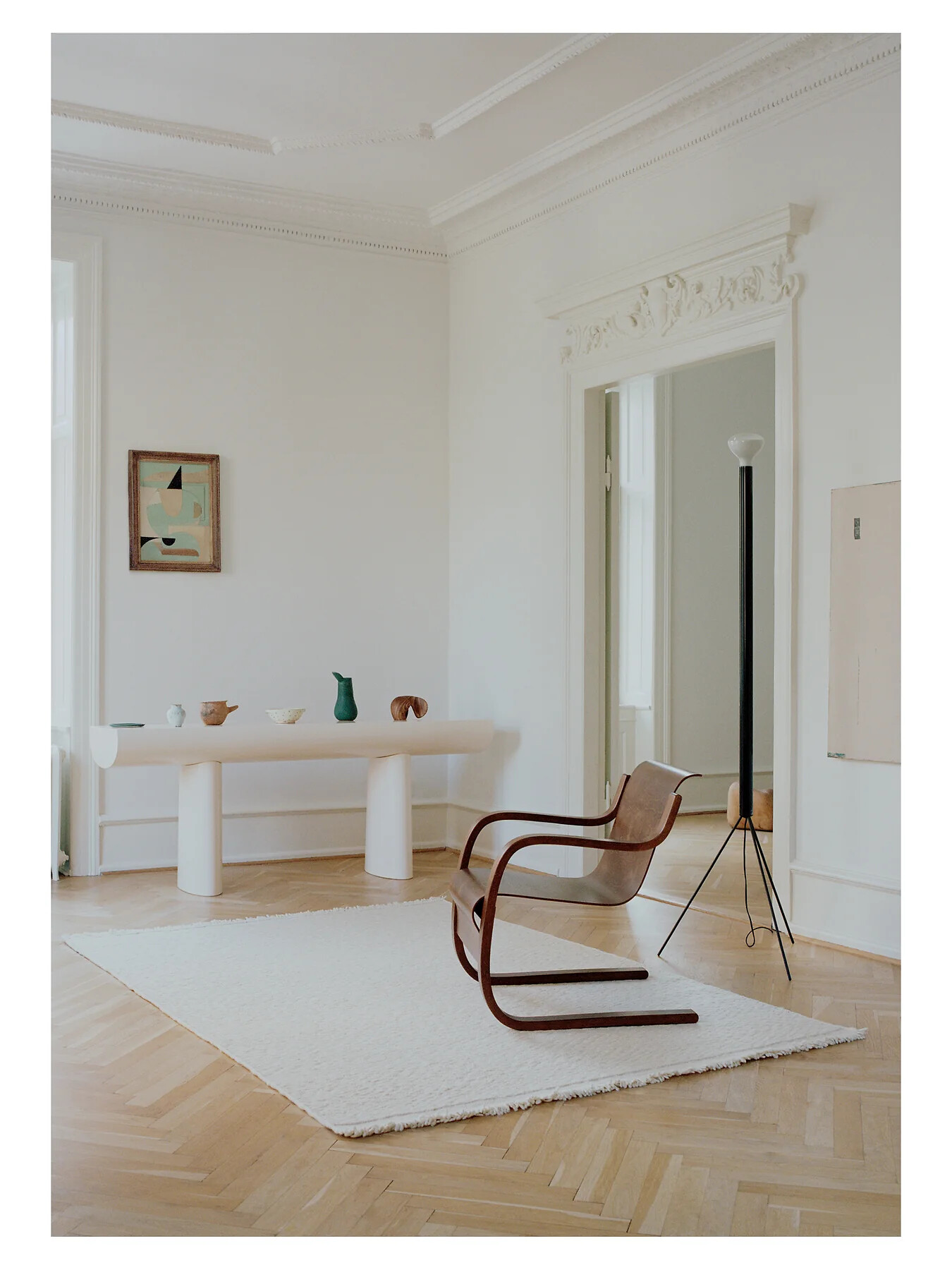 Weißer Teppich in hellem Raum mit Holzstuhl und Designleuchte auf Fischgrätboden