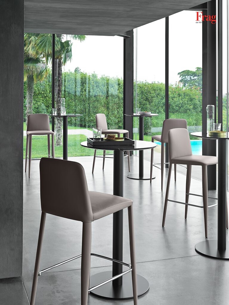 Hochlehner-Barhocker an schwarzen Stehtischen in verglastem Raum mit Gartenblick