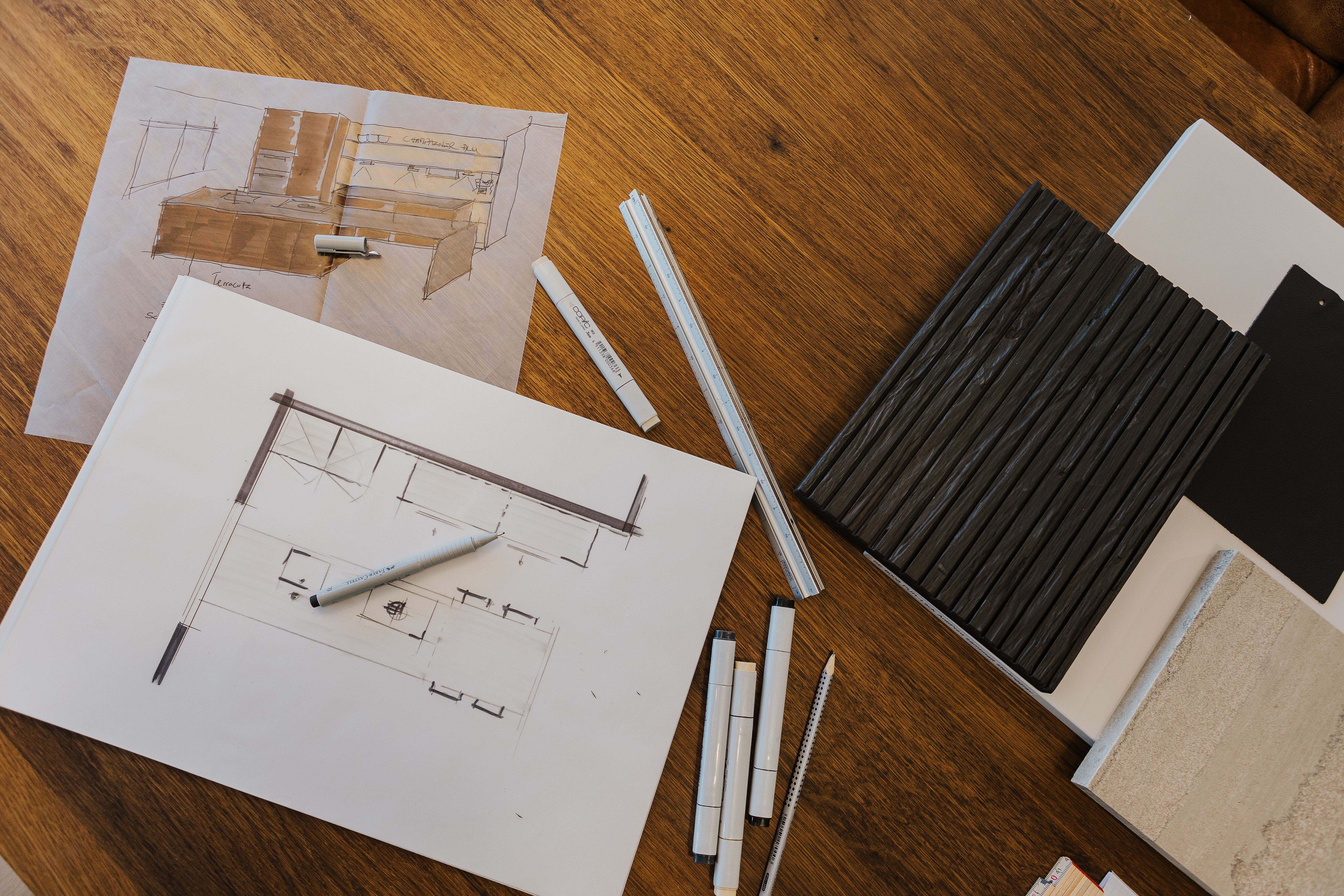Küchenentwurf mit Planungszeichnungen, Materialmustern und Leisten auf einem Holztisch arrangiert