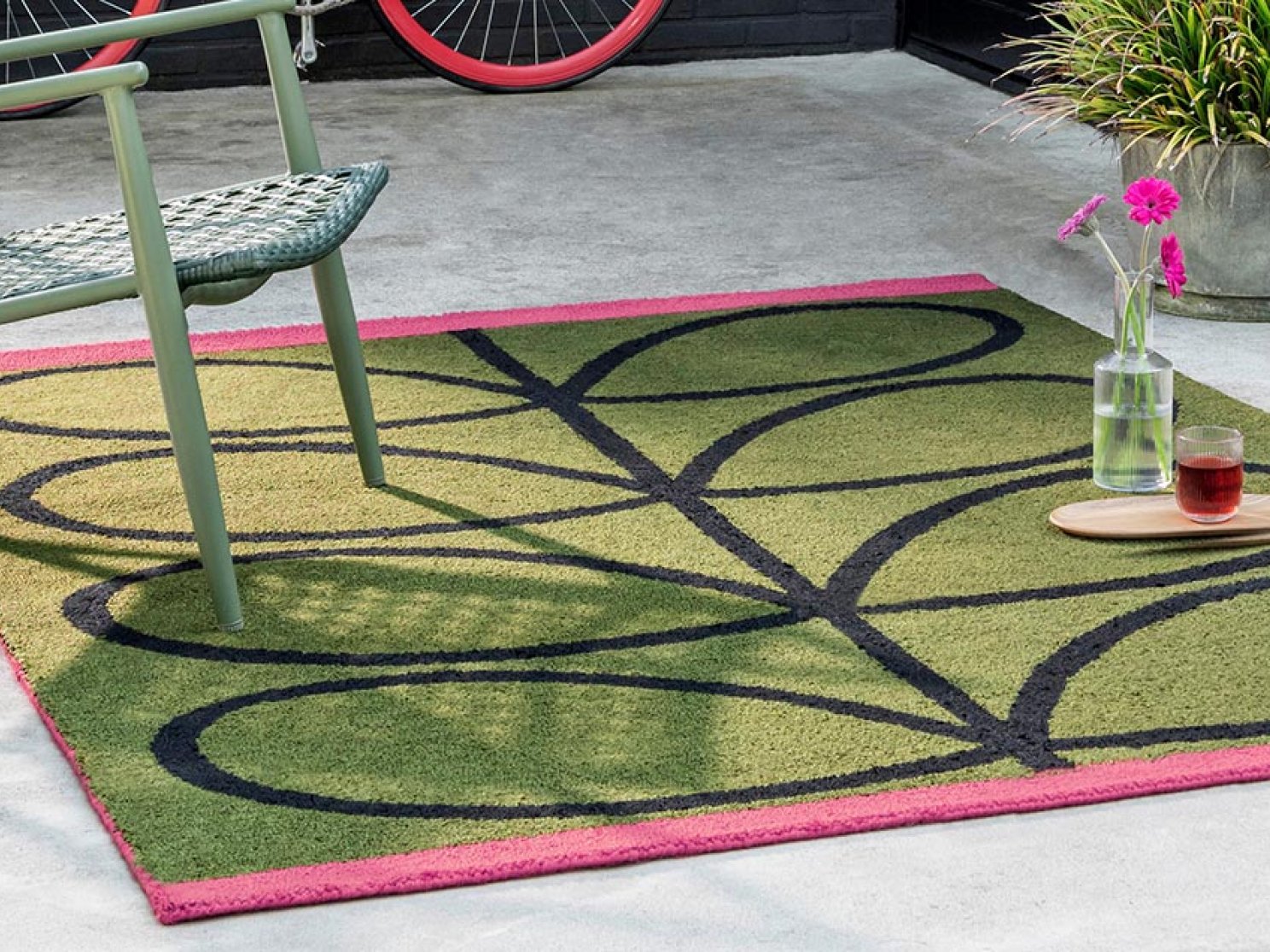 Grün-pinker Outdoor-Teppich mit großem schwarzem Linienmuster auf Terrasse