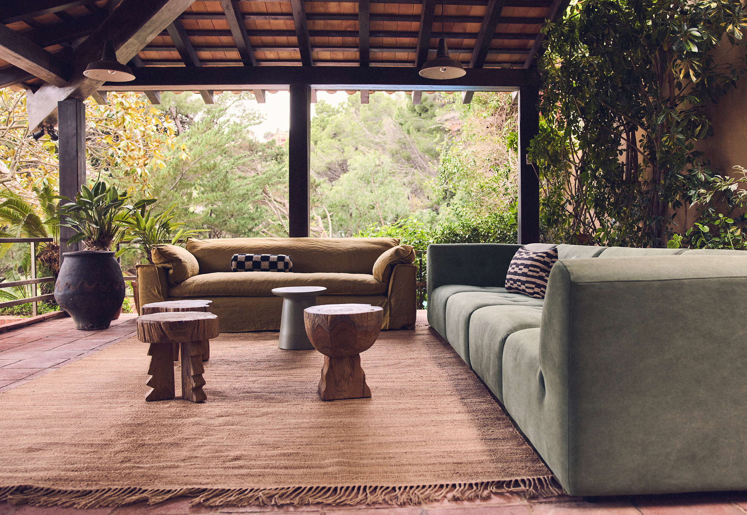 Zwei Polstersofas in Grüntönen auf Terrasse mit Holztischchen und Ausblick ins Grüne