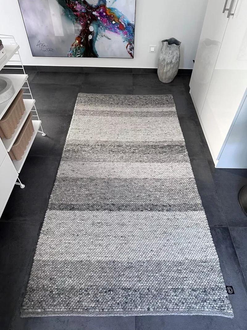 Läufer in Grauabstufungen auf dunklem Fliesenboden neben weißem Sideboard