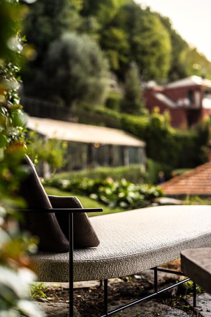 Daybed auf Terrasse, im Hintergrund ein Garten mit Wohnhaus