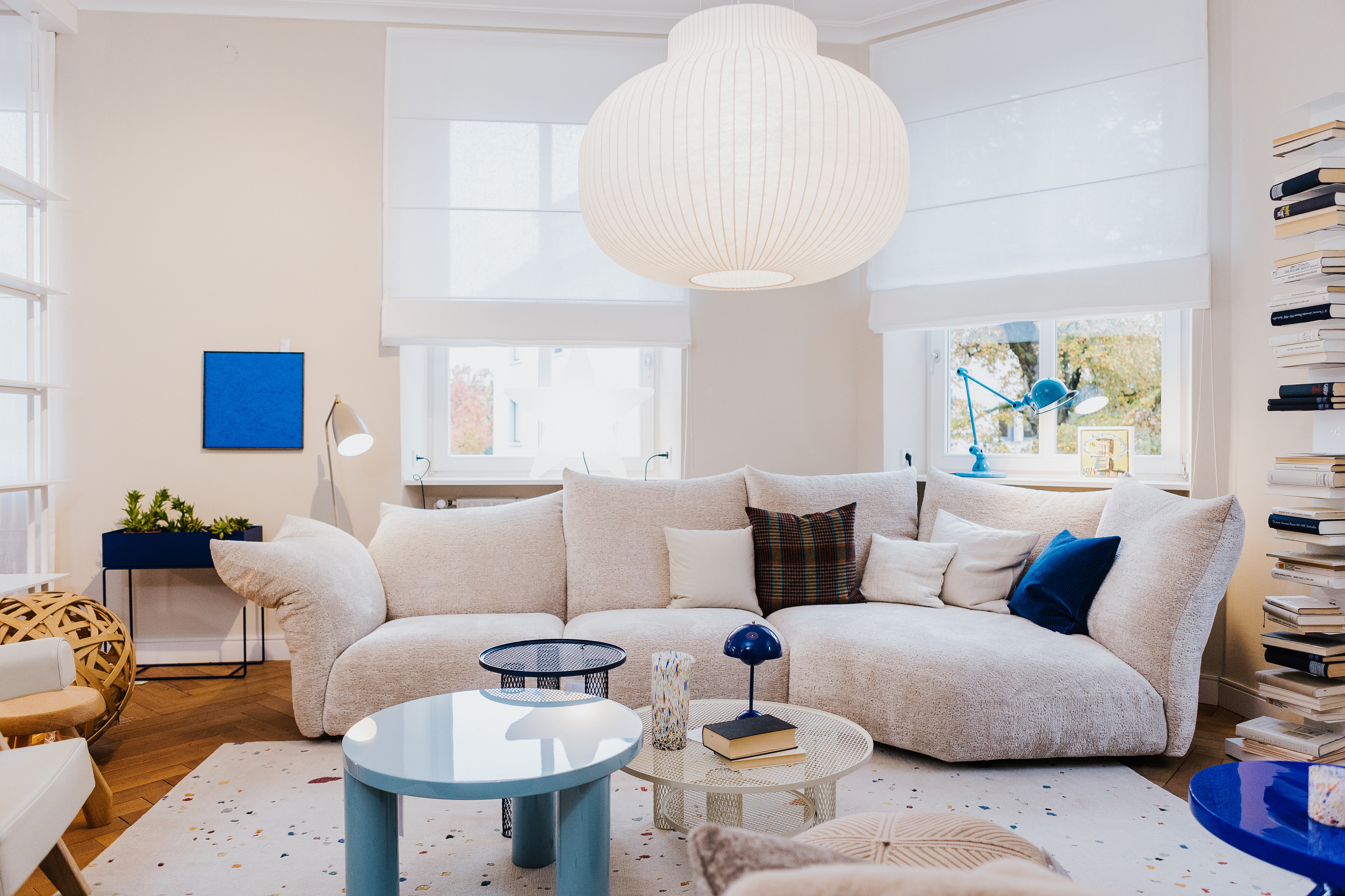 Wohnbereich mit organisch geformtem Sofa Standard von Edra und farbigen Beistelltischen