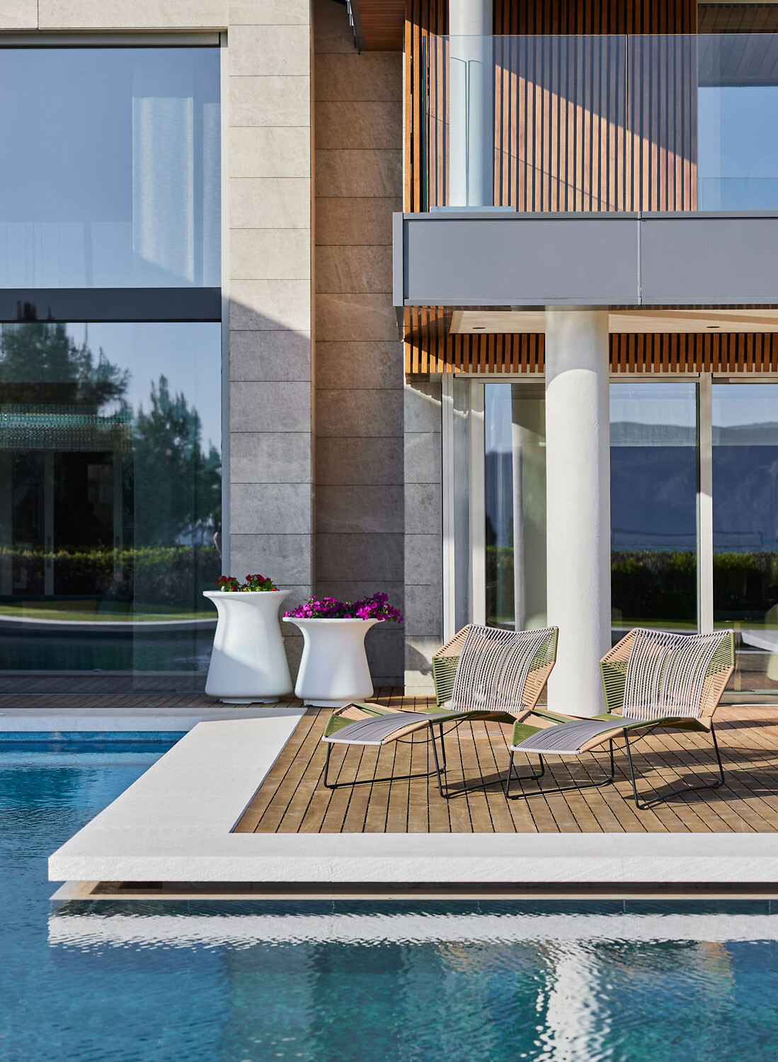 Zwei Liegen von Moroso auf Holzdeck mit Blick auf den Poolbereich