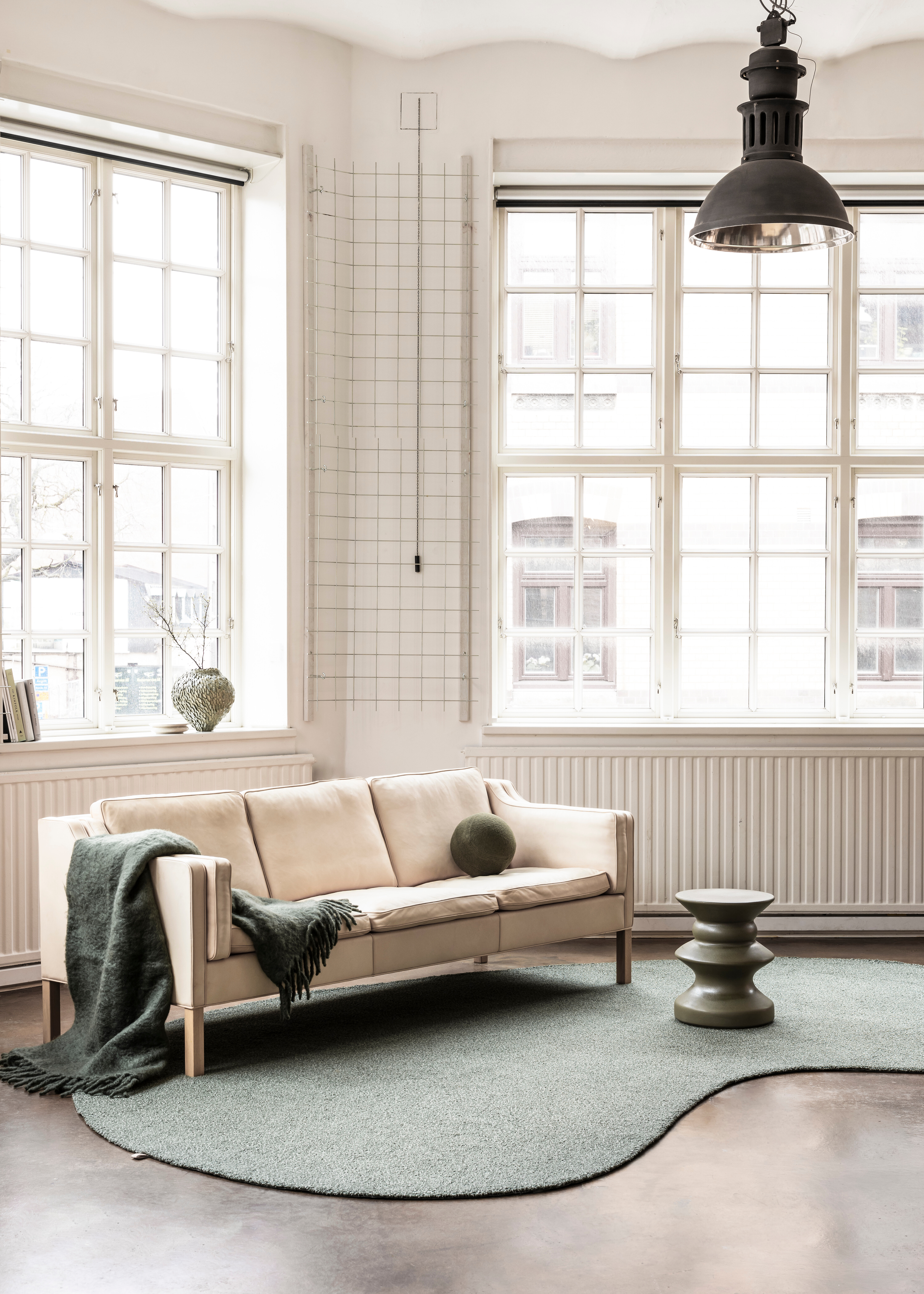 Wohnraum mit organisch geformtem Kasthall-Teppich in hellem Grün und Sofa am Fenster