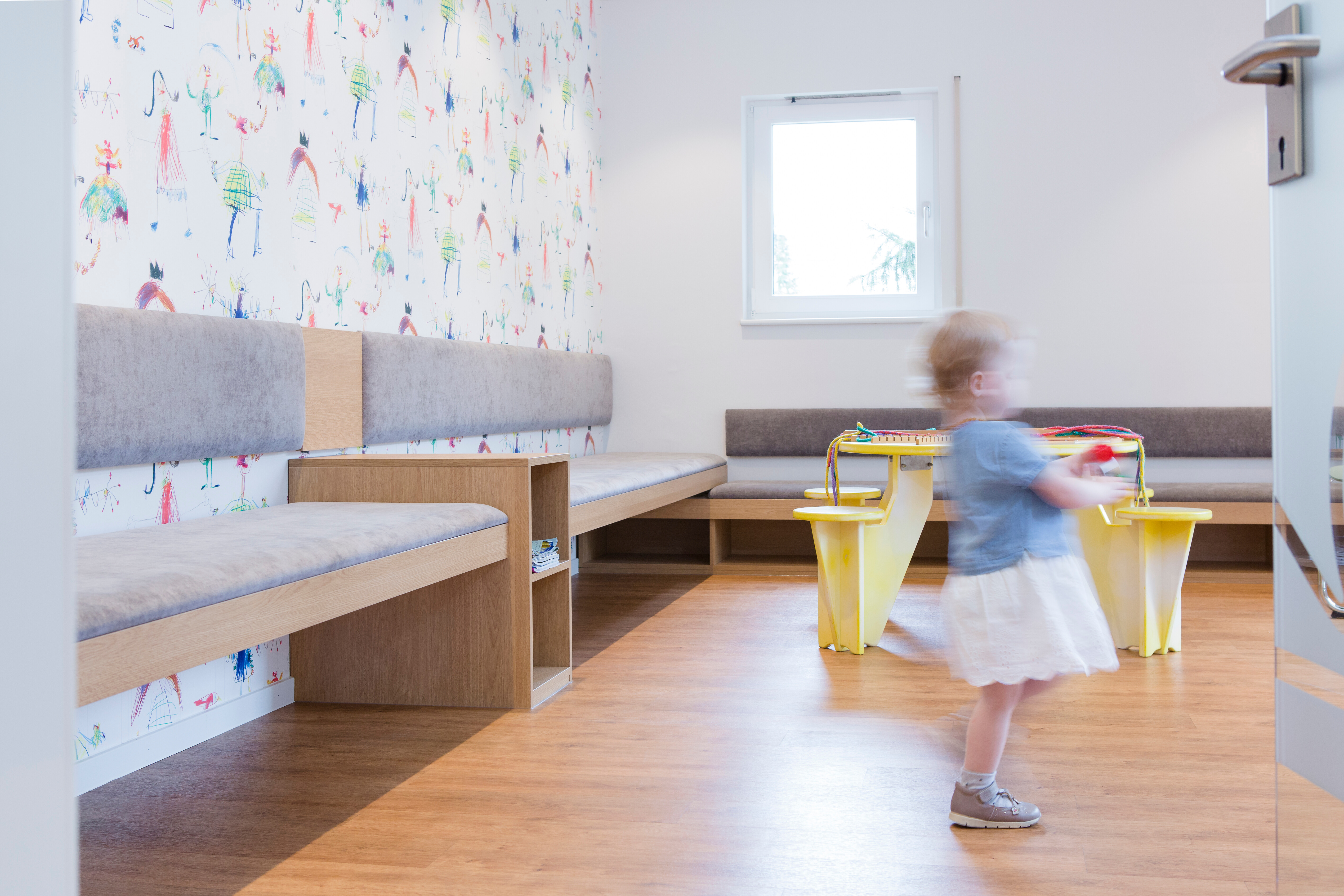 Die bunte und fröhliche Tapete verleiht dem Wartezimmer eine verspielte Stimmung.