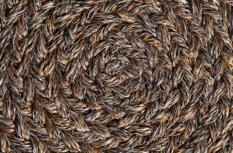 Kreisförmig geflochtene Struktur eines Sisalteppichs in Braun- und Grautönen
